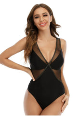 Woman in a black one-piece swimsuit with mesh insets and a plunging neckline.