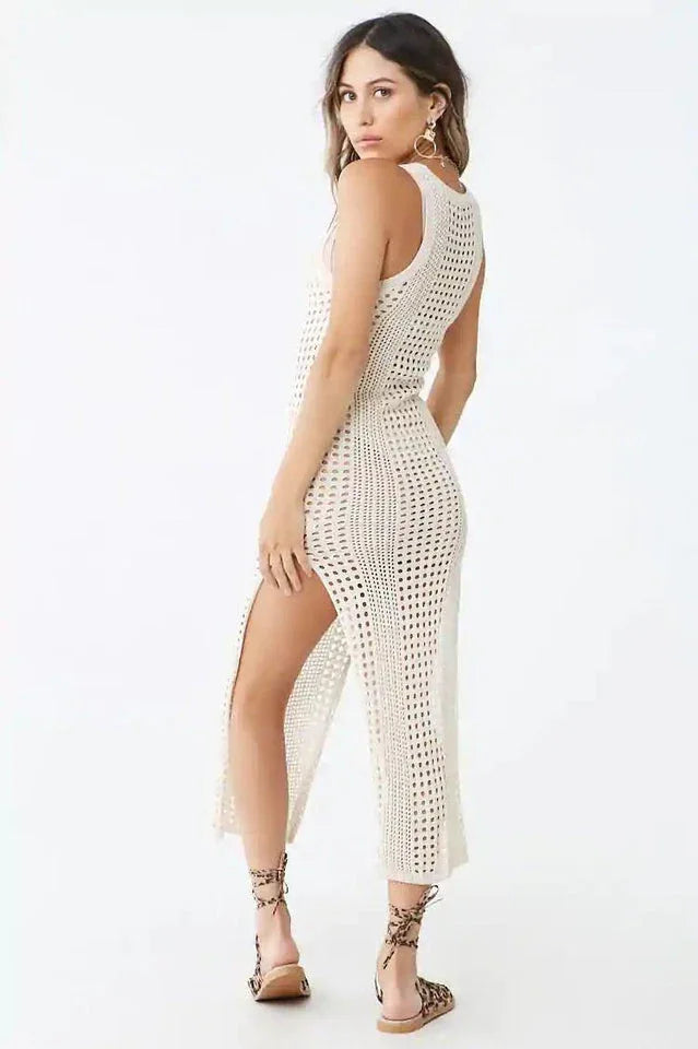 Back view of a woman wearing a cream crocheted knit sleeveless maxi dress with a high slit.