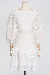 Mannequin displaying a white off-the-shoulder smocked crop top with sheer lace sleeves and a white tiered lace skirt