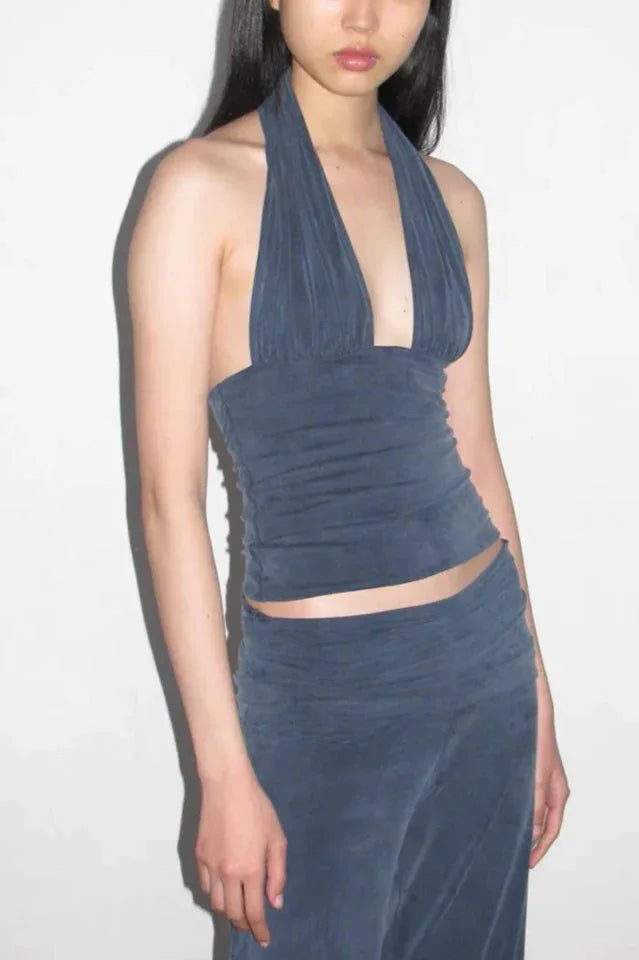 Woman wearing a dark blue halter neck crop top with a deep V-neckline and matching dark blue wide leg pants.