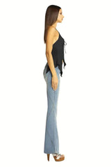 Side view of a woman wearing a black halter top and light wash flared jeans.