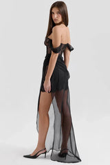 Side view of a woman in a black off-the-shoulder lace corset dress with a sheer flowing skirt