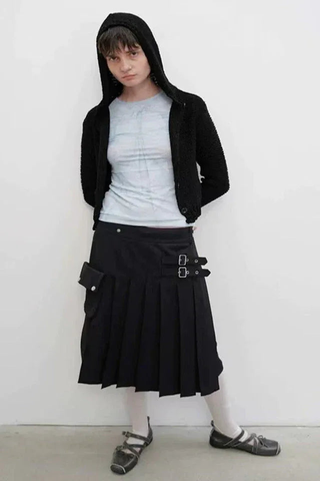 Model wearing a light blue tie-dye long-sleeve top, black hooded cardigan, and a black pleated skirt with buckle details and a pocket.