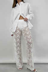 Front view of a woman in a white oversized button-down shirt and white lace wide-leg pants, posing.