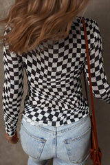 Close-up back view of a woman wearing a black and white checkerboard long-sleeved mesh top and blue jeans.