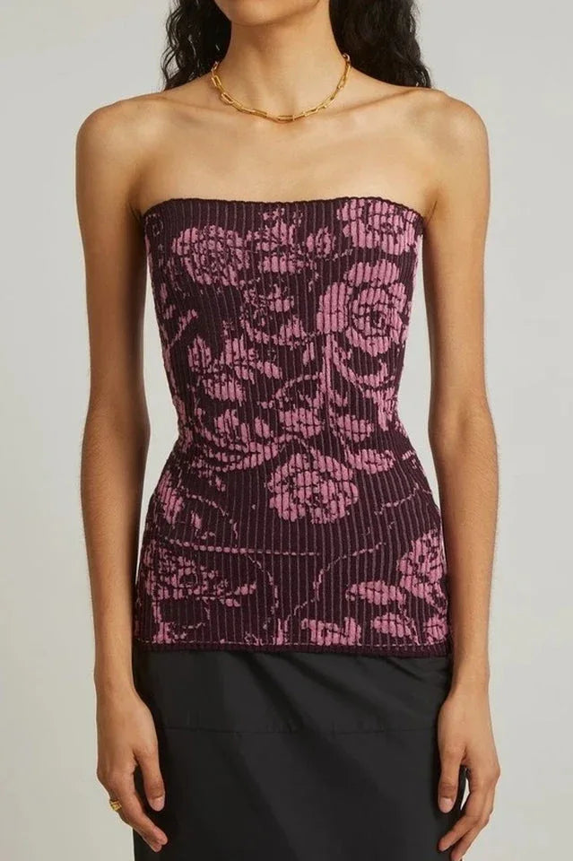 Model wearing a dark purple strapless top with a pink floral pattern and vertical ribbing, paired with a black skirt.