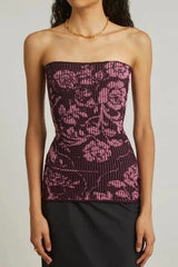 Model wearing a dark purple strapless top with a pink floral pattern and vertical ribbing, paired with a black skirt.