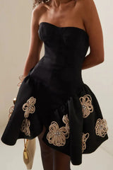 Close-up of a black strapless dress with floral embellishments on the skirt