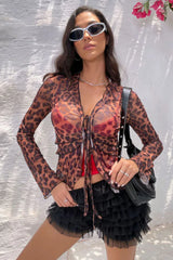 Front view of a woman in a leopard print sheer mesh top and black ruffled shorts.