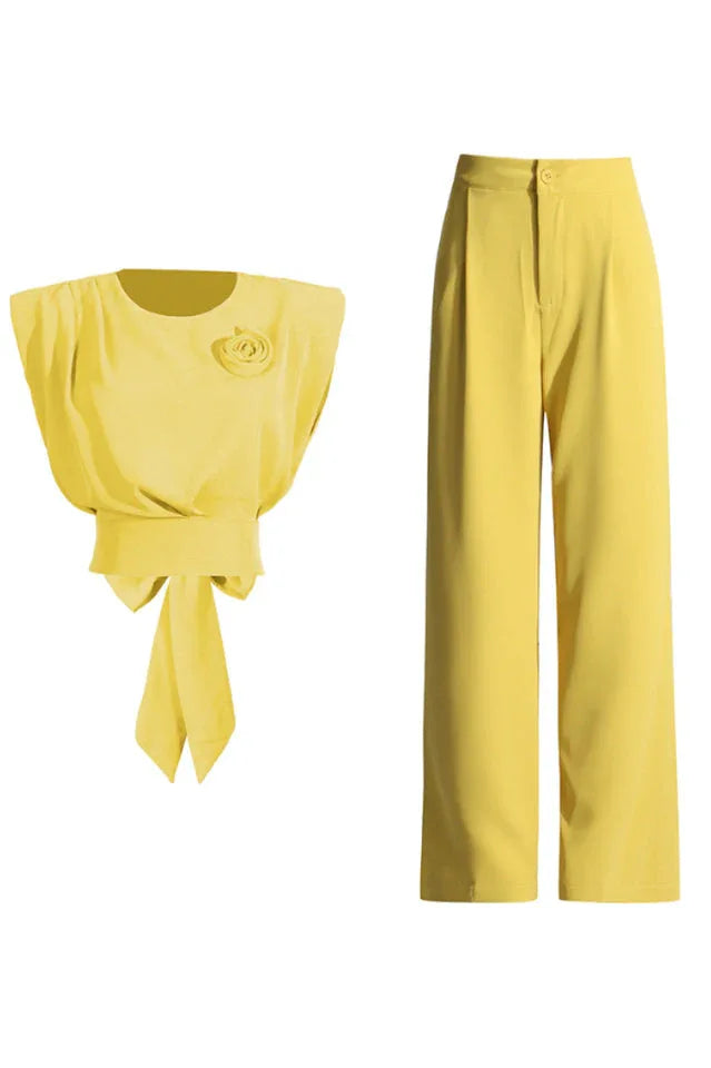 A yellow cropped top with a rose embellishment and bow detail, shown next to a pair of yellow wide-leg pants.