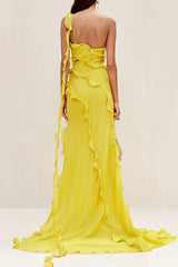 Rear view of a model in a flowing yellow one-shoulder chiffon gown with ruffled accents and a train.