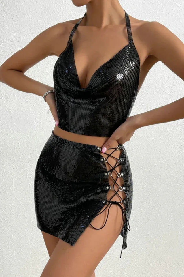 Front view of a woman wearing a black metallic mesh halter top and mini skirt with a high slit and lace-up detail.
