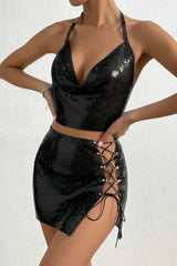 Front view of a woman wearing a black metallic mesh halter top and mini skirt with a high slit and lace-up detail.