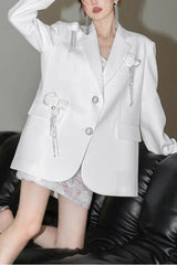 Model posing in a white embellished blazer and a patterned skirt.