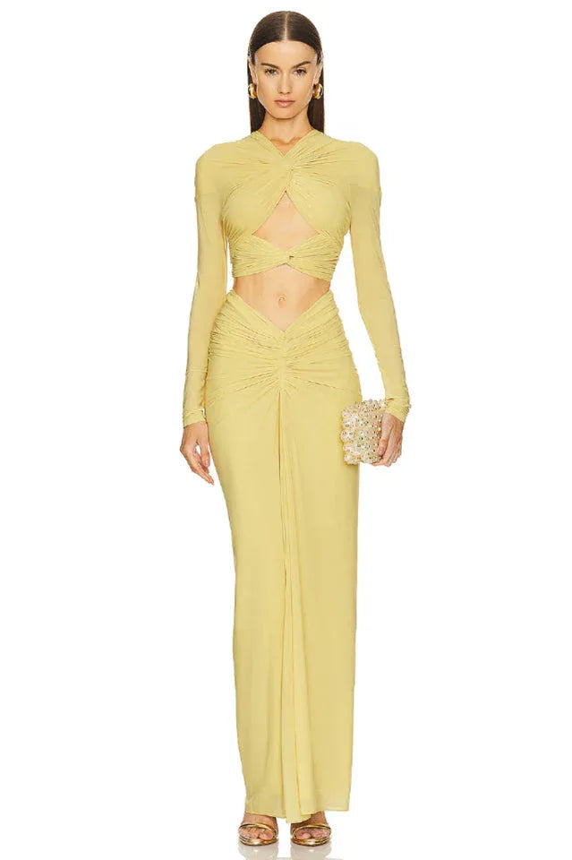 Full-length studio shot of a yellow ruched jersey gown with a twisted front and cut-out torso, held by a mannequin
