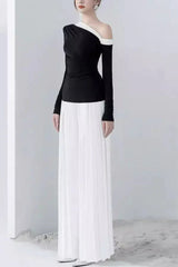 Side view of a model in a black asymmetrical top and white wide-leg pleated pants.