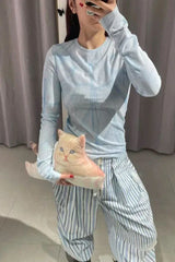 Model wearing a light blue tie-dye long-sleeve top and striped trousers, holding a cat-shaped accessory.