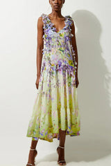 Woman wearing a pastel yellow and purple floral print midi dress with ruffled straps and tiered skirt.