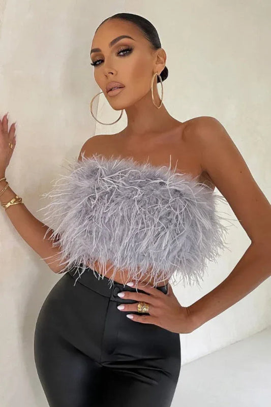 Woman wearing a grey strapless feather crop top and black pants