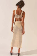 Woman wearing a cream crochet knit crop top and matching maxi skirt, back view.