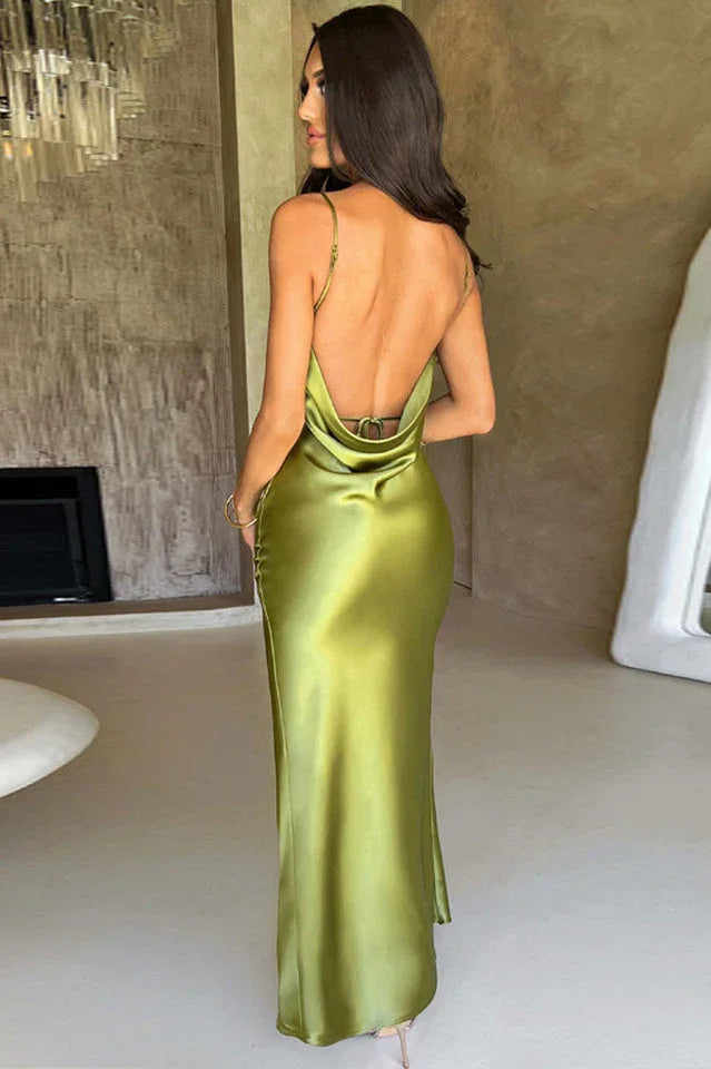 Back view of a woman wearing a long olive green satin slip dress with spaghetti straps and an open back.