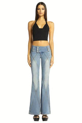 Woman wearing a black crop halter top with light wash flared jeans.