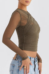 Side view of a woman wearing a green ruched mesh top and light wash jeans.