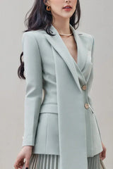 Close-up of a woman wearing a light blue blazer with a shawl lapel and two gold buttons.