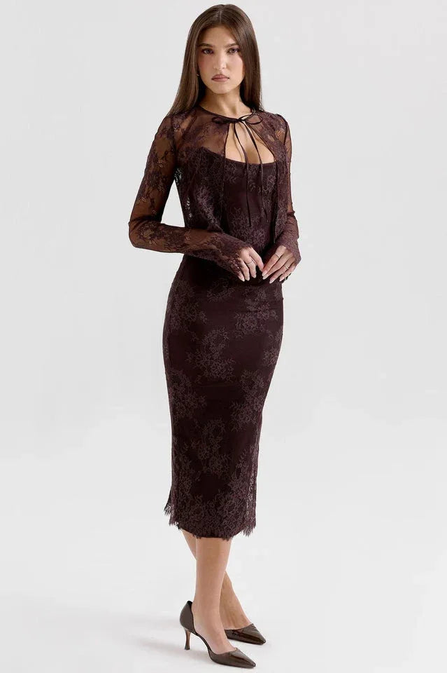 Woman in a dark brown lace midi dress and bolero jacket, posing with hands at her side