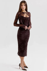 Woman in a dark brown lace midi dress and bolero jacket, posing with hands at her side