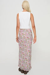 Back view of a woman in a white sleeveless vest and a floral maxi skirt.