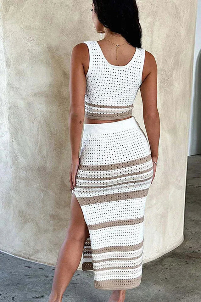 Woman wearing a white and tan striped knit cropped tank top and matching midi skirt with a side slit, back view