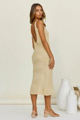 Side view of a woman wearing a beige knit midi dress with a scoop back and high slit