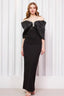 Model posing in an elegant black floor-length dress with an off-the-shoulder bow design