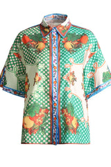 Front view of a fruit print short-sleeve collared shirt with a polka dot pattern.