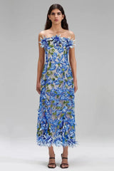 Woman wearing a blue and green strapless midi dress with floral embellishments and a trumpet skirt.
