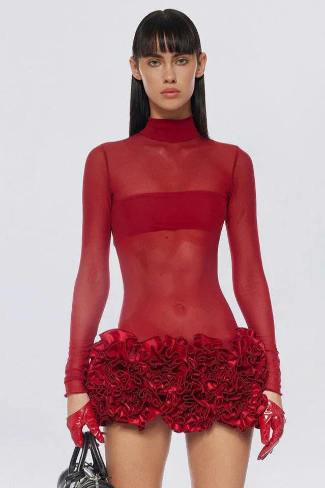 Model wearing a red sheer mini dress with ruffled hem and gloves