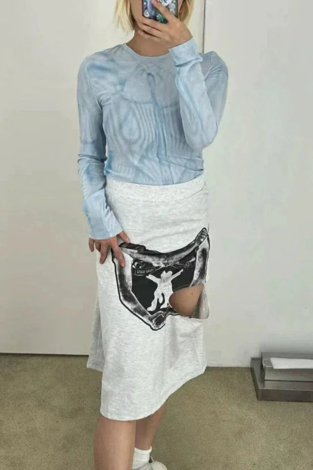 Model wearing a light blue tie-dye long-sleeve top and a grey asymmetrical skirt with a graphic print cutout.