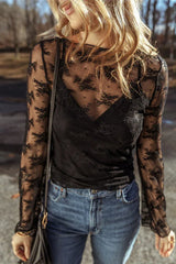 Woman wearing a black lace long-sleeved top with a scoop neckline and bell sleeves, paired with blue denim jeans.