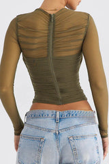 Back view of a woman wearing a green ruched mesh top and light wash jeans, showing the zipper closure.