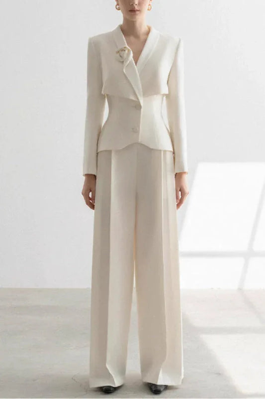 Woman wearing a white tailored suit with a peplum jacket and wide-leg trousers, front view.