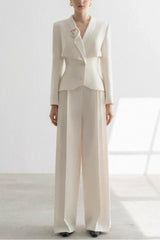 Woman wearing a white tailored suit with a peplum jacket and wide-leg trousers, front view.