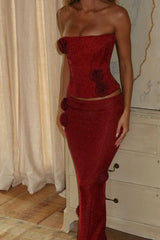 Front view of a woman in a red sparkly strapless corset top and maxi skirt with rose details.