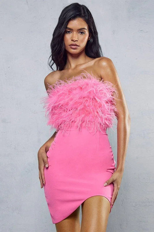 Woman wearing a pink strapless dress with feather trim on the bodice and an asymmetrical hem.