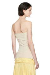 Back view of a woman wearing a cream strapless tube top with a yellow skirt.