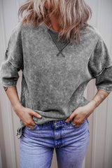 Woman wearing a grey acid wash oversized t-shirt with blue jeans, hands in pockets