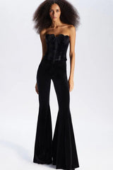 Full body shot of a model in a black velvet corset and flared pants