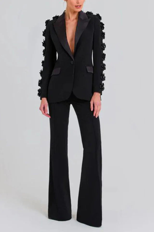 Woman wearing a black formal suit with floral embellished sleeves and flared trousers