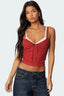Front view of a red cropped tank top with lace trim and a tie front, paired with dark wash jeans.