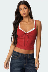 Front view of a red cropped tank top with lace trim and a tie front, paired with dark wash jeans.